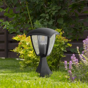 Garden lighting – lights on the solar battery on a green lawn next to a paved path